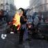 A demonstrator wearing a costume stands in front of burning flames, in Paris