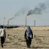 FILE PHOTO: People walk near farmland by the Zubair oil field as gas flares rise in the distance, in Zubair Mishrif, Basra