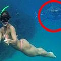 Djevojka pozira u moru dok joj iza njenih leđa prilazi morski pas