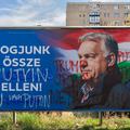 Defaced Fidesz billboard with anti-war slogan and graffiti referencing Putin and Trump in Budapest during Hungary’s 2026 election campaign.