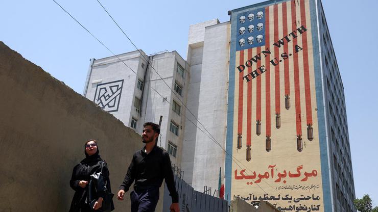 People walk near an anti-U.S. mural in Tehran