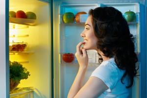 Žena proučava hranu u hladnjaku