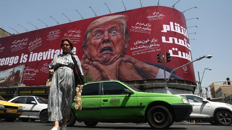 People walk near a billboard depicting U.S. President Donald Trump on a building in Tehran