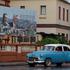 A vintage car passes by a billboard in Havana
