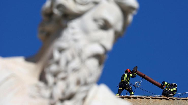 Firefighters work to set a chimney on the roof of the Sistine Chapel, ahead of the conclave, at the Vatican